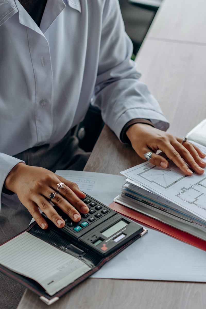 Person using a calculator beside a stack of documents
